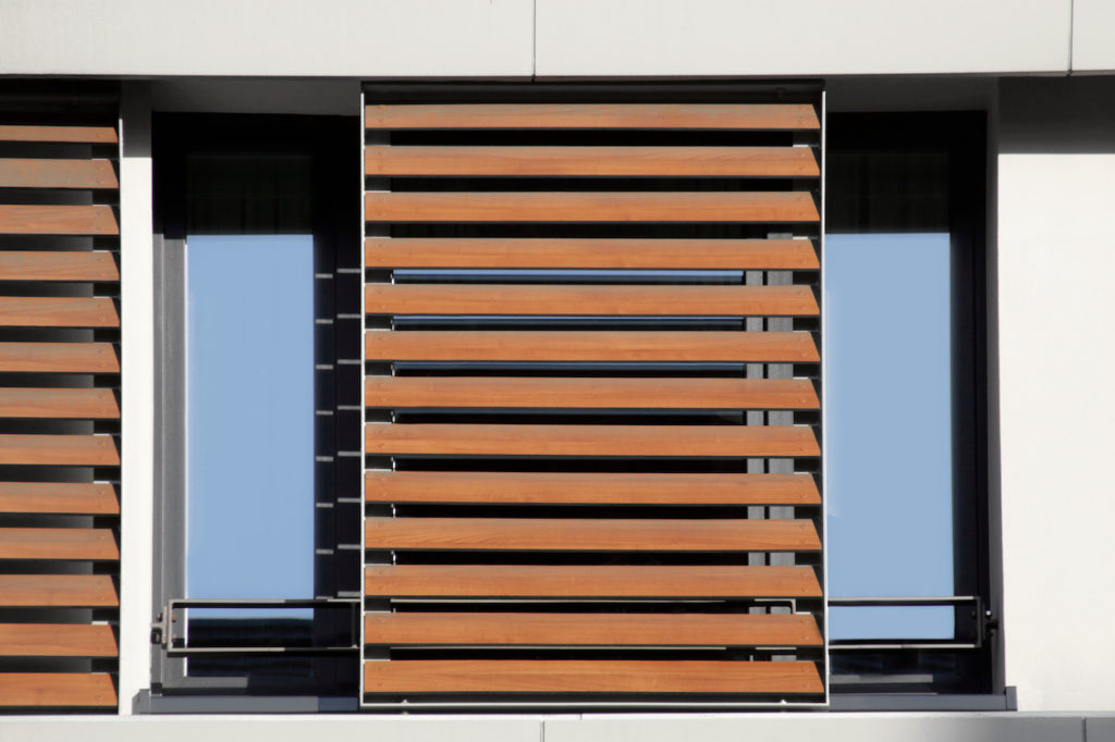 Light brown louvers / blinds over window. Lath structure. Abstract modern architecture background photo. Office or residential building exterior or interior fragment.