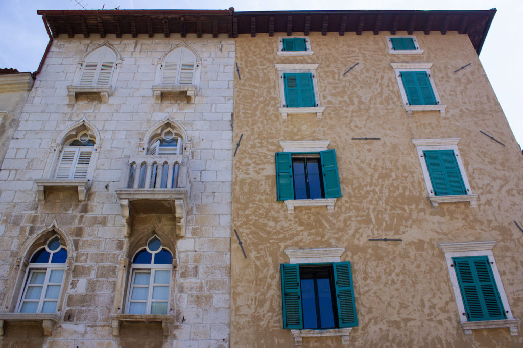 Two different facades of old houses with green shutters in the old town of Porec (Parenzo), in the Istrian Peninsula, Croatia