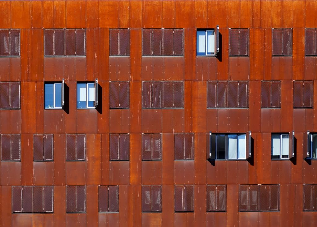 deep red wall with winows with  open and closed shutters as backdround