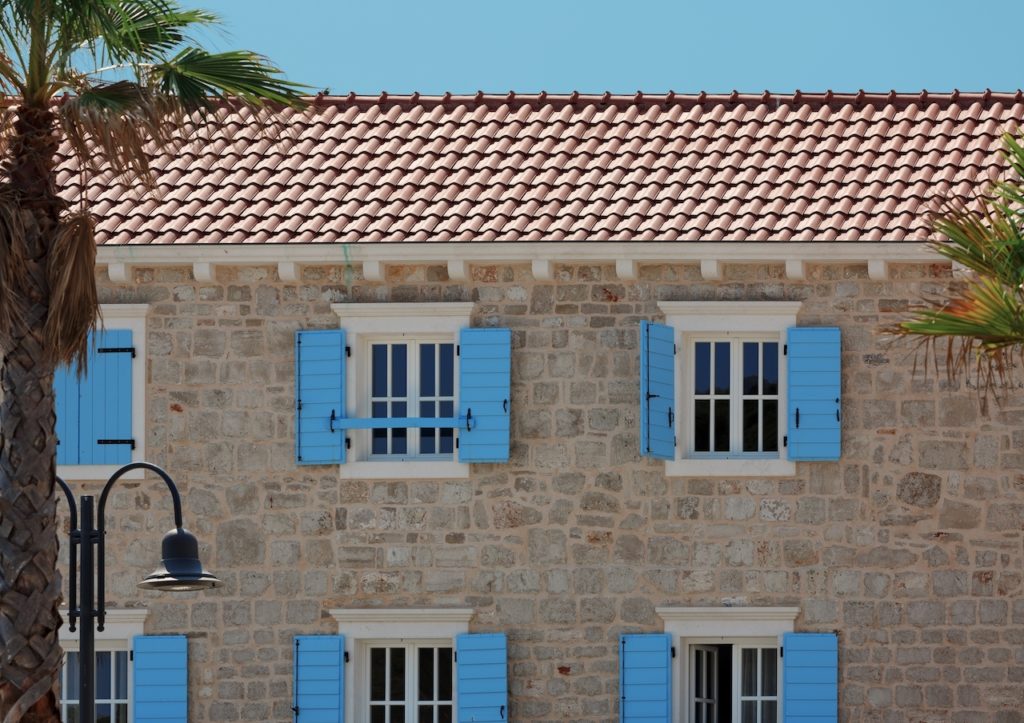 Facade of a typical old mediterranean building with windows decorated with blue shutters. Croatia