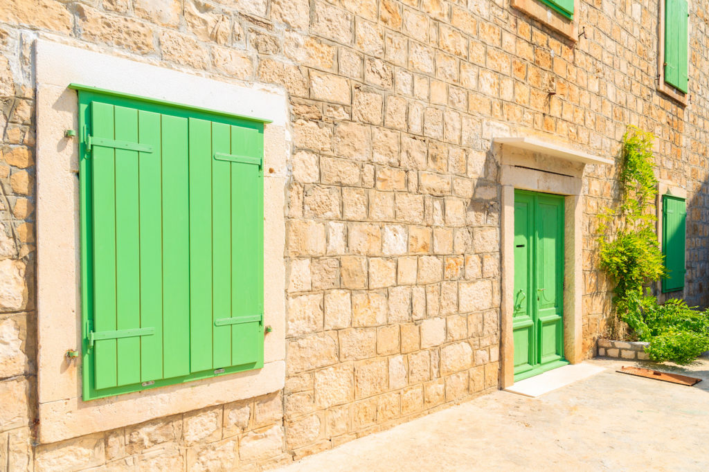 Green window shutter and door of old house in Splitska village, Brac island, Croatia